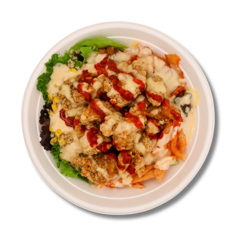 Fried chicken, pasta, lettuce, and corn in a bowl, topped with creamy white and red sauces.