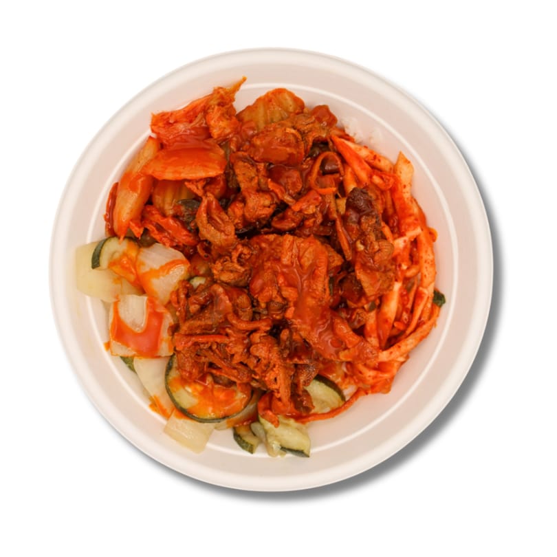 Spicy red meat, kimchi, and sliced vegetables in a white round bowl.