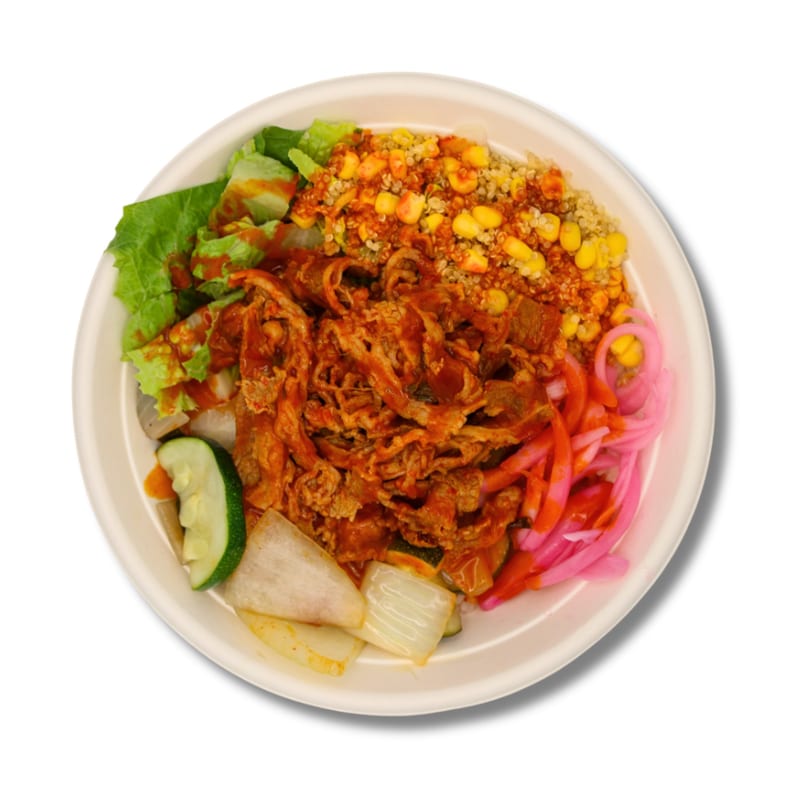 Colorful food bowl with sauced meat, lettuce, quinoa, corn, pickled onions, and cucumber.