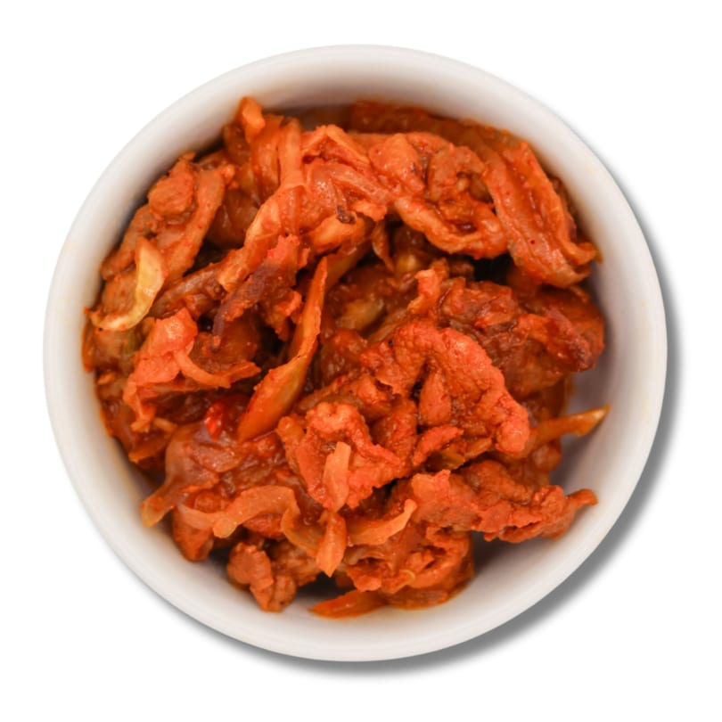 Vibrant red marinated meat and sliced onions in a white bowl.