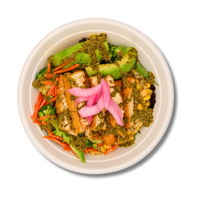Tofu bowl with avocado, broccoli, carrots, corn, grains, green sauce, and pickled onions.